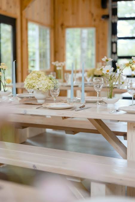 Wood tables set with pale blue candles and white hydrangea centerpieces