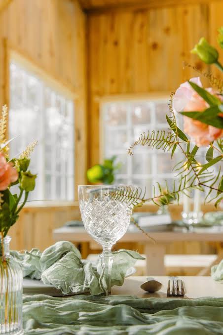A cut-crystal glass and peach florals on a sage green table runner