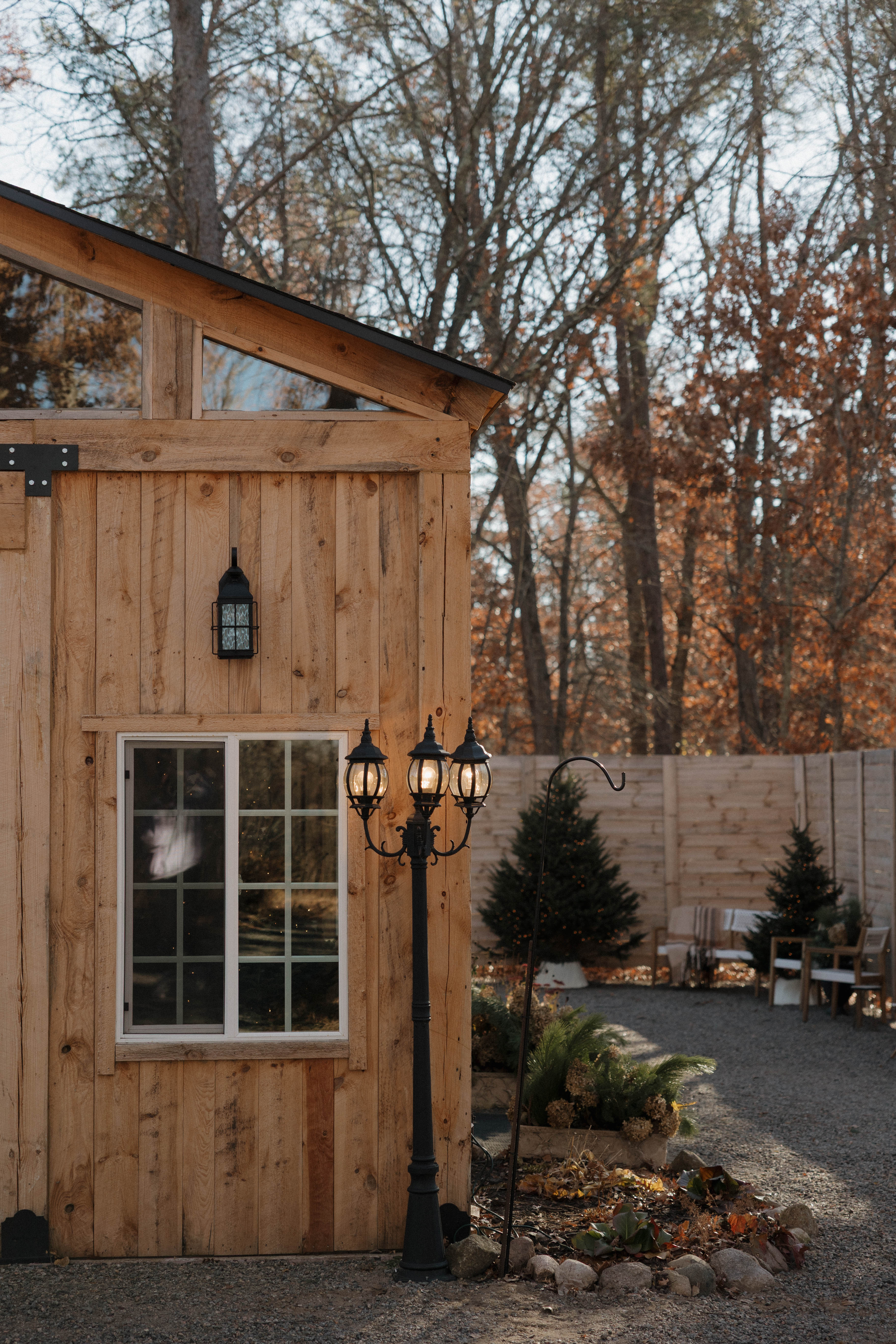 The timber cottage glowing among autumn trees with lanterns outside