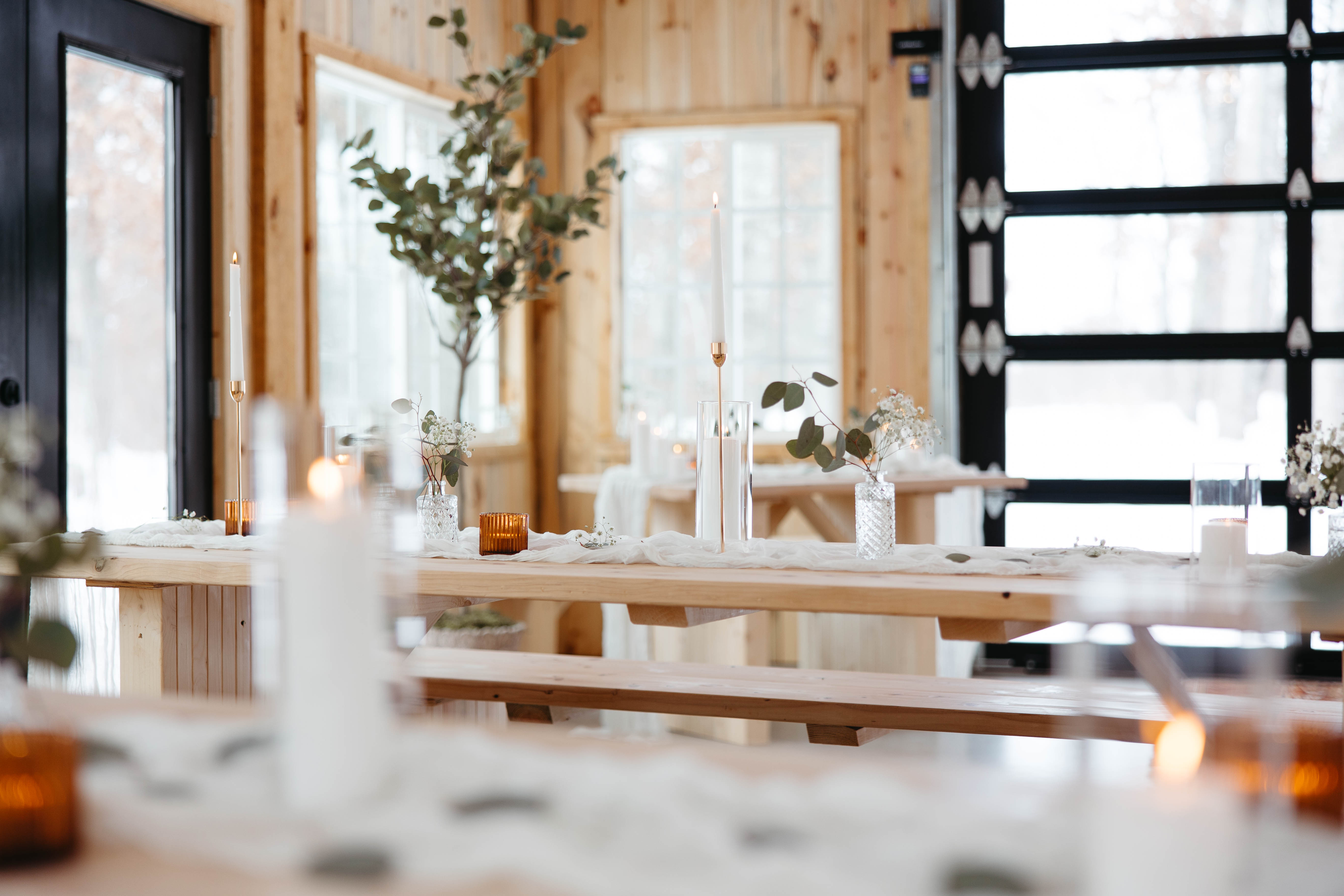 An elegant wedding reception table with candles, greenery, white linens, and warm wood