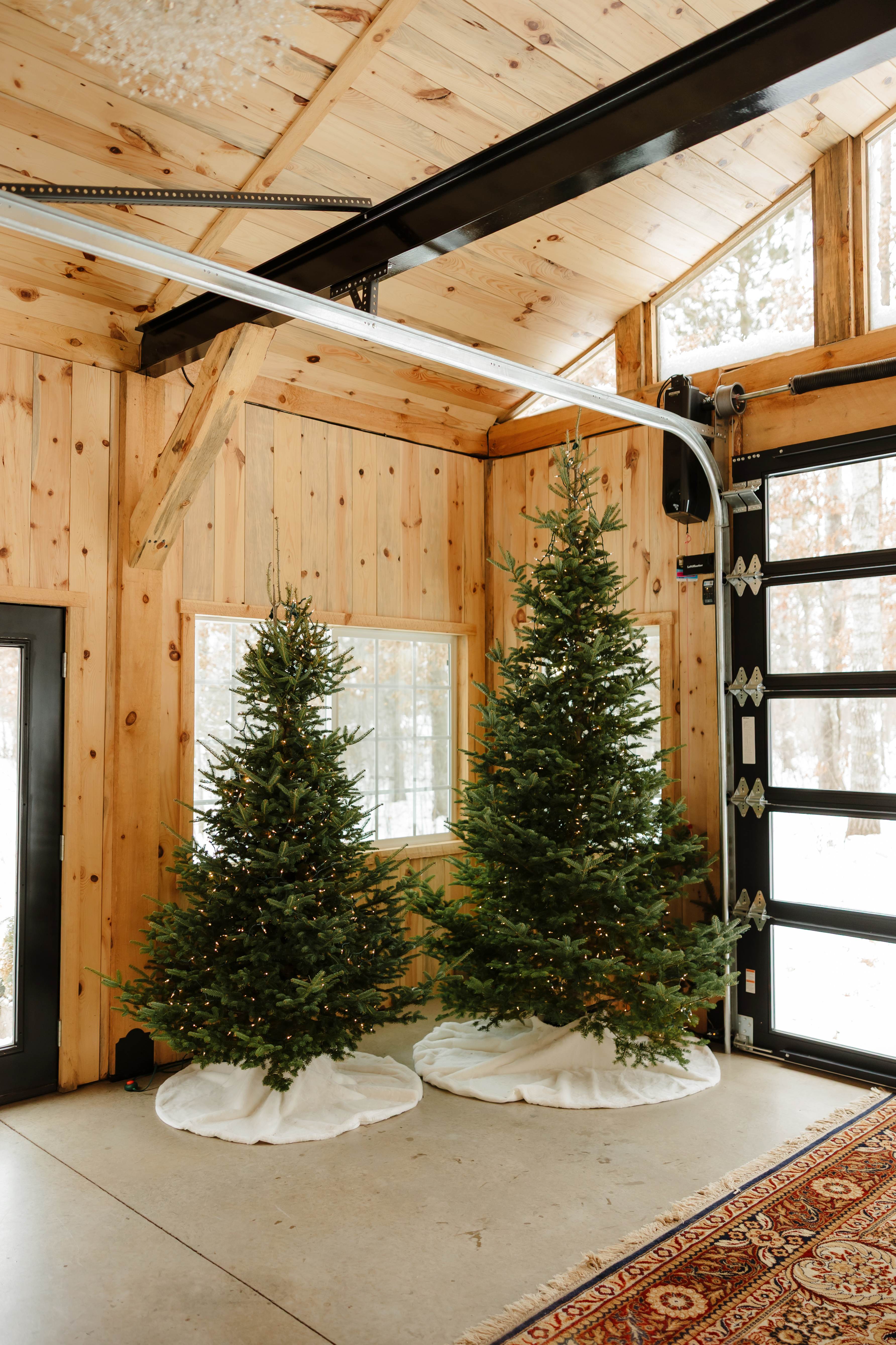 Real Christmas trees decorated with warm white lights inside the timber cottage